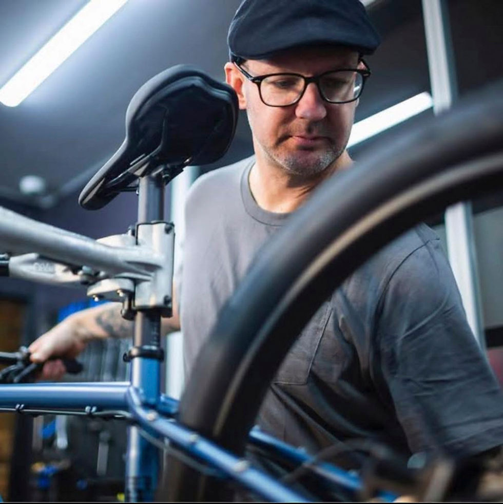 Portrait of a bike mechanic working on a blue bike in a workshop