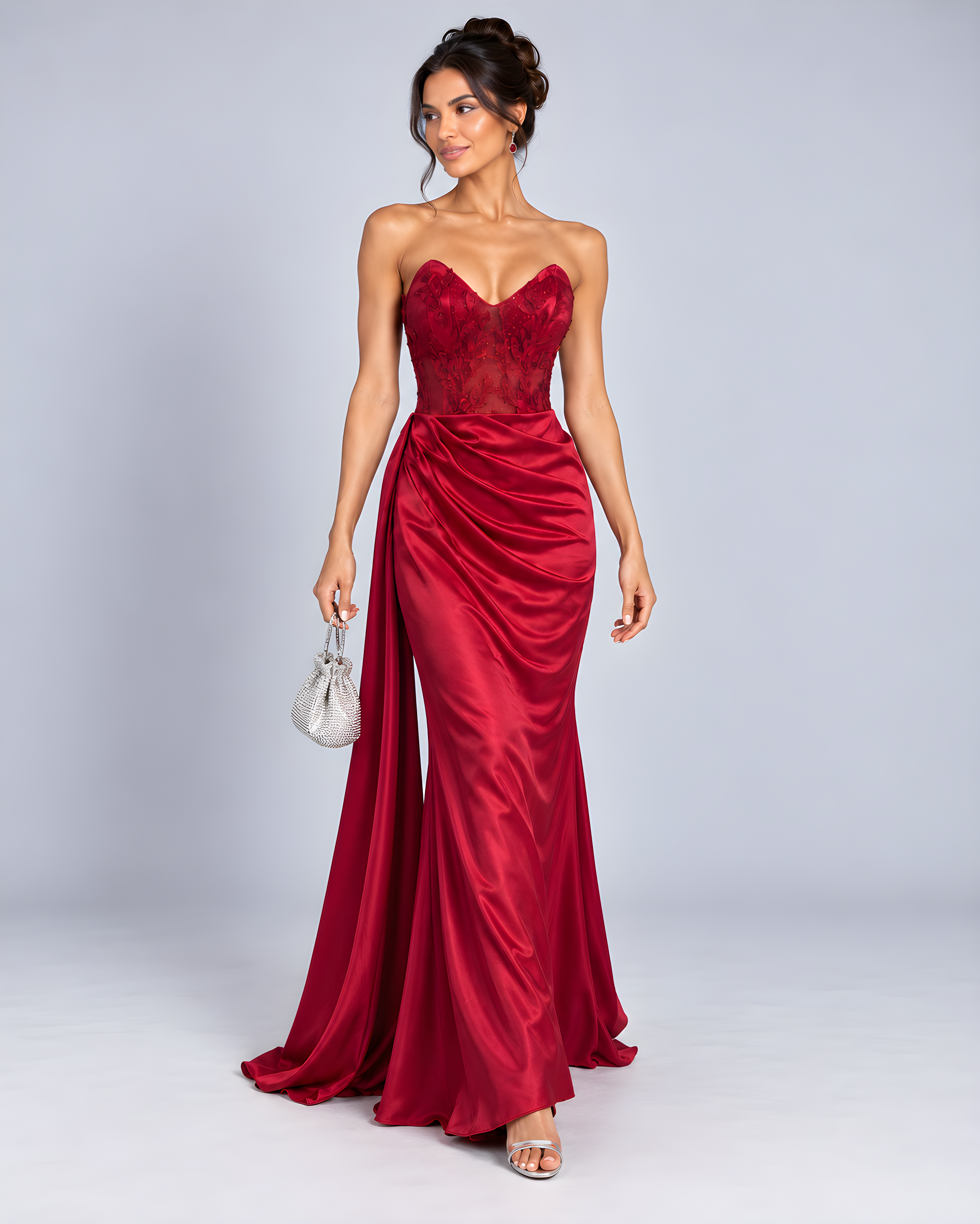 Front view of model wearing Red strapless satin evening gown with an embroidered sheer corset bodice and sweep train.
