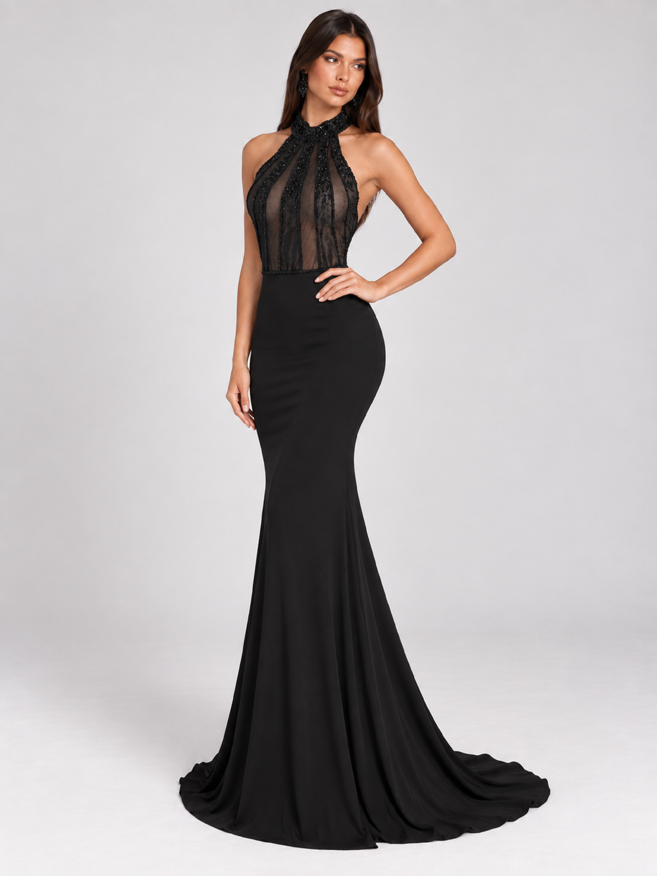 Side View of model wearing Black halter mermaid evening gown with a sheer beaded illusion bodice and open back