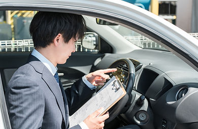 チェック表を使って車の査定をする日本人男性