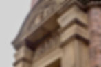 Ornate stone bank facade with the word "BANK" inscribed. Features column details and a decorative arch. Calm, historical ambiance.