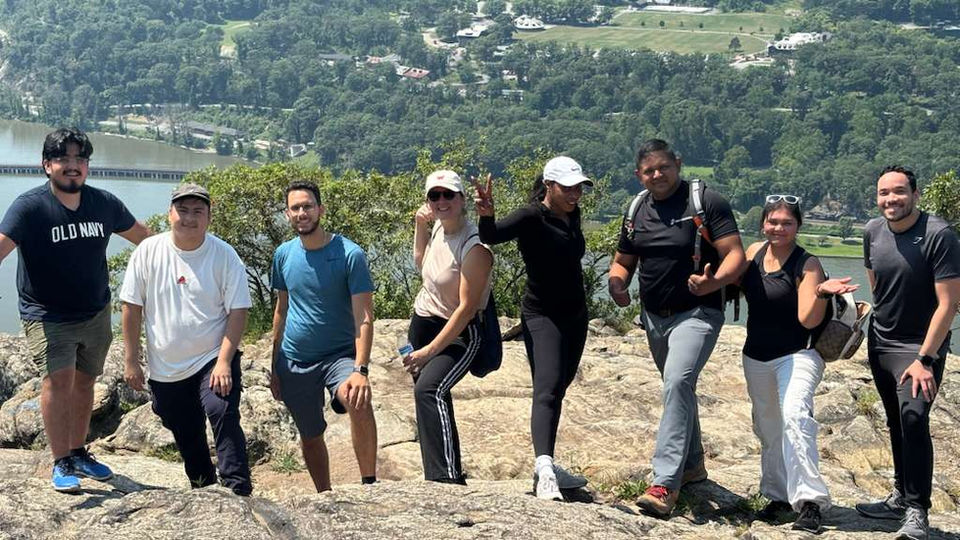 The team posing together outdoors on a scenic hilltop.
