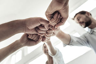Team of people bumping fists together for a successful project. Beauchamp Team Growth.
