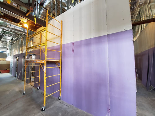 Yellow scaffolding next to a purple and white wall.