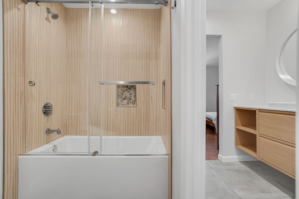 Modern bathroom remodel with a tub-shower combination, vertical wood-look wall tile, frameless glass shower screen, recessed niche, and floating wood vanity.