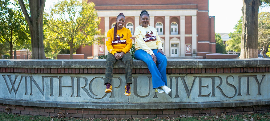 Female models sitting on Winthrop sign