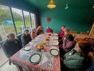 A group of visitors and volunteers sitting together ready to share a meal