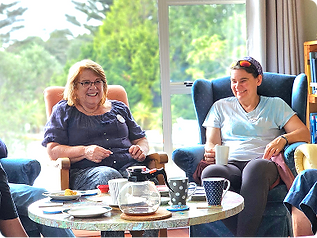 A visitor and volunteer laughing over coffee