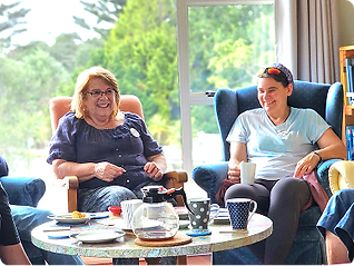 A visitor and volunteer laughing over coffee