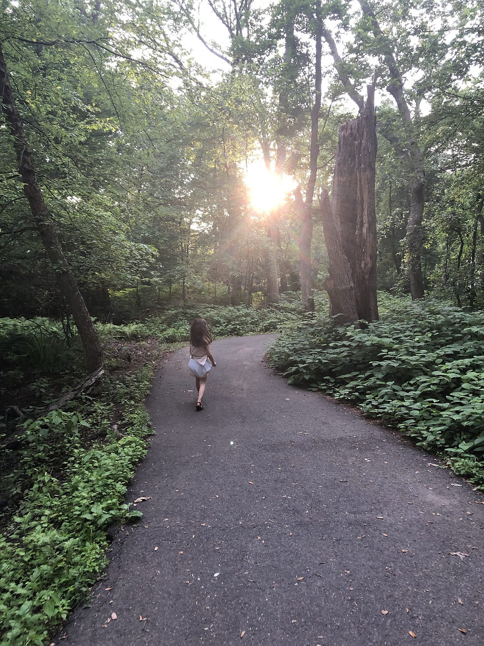 A child runs through the woods as sun filters through the trees.