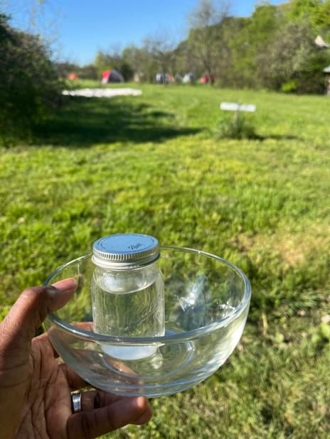 A hand holds a crystal bowl and a ball jar of water