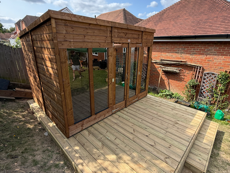 a wooden shed with sliding glass doors sits on a wooden deck