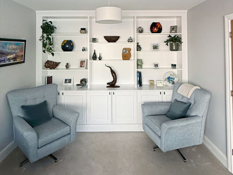 a living room with two chairs and a bookshelf