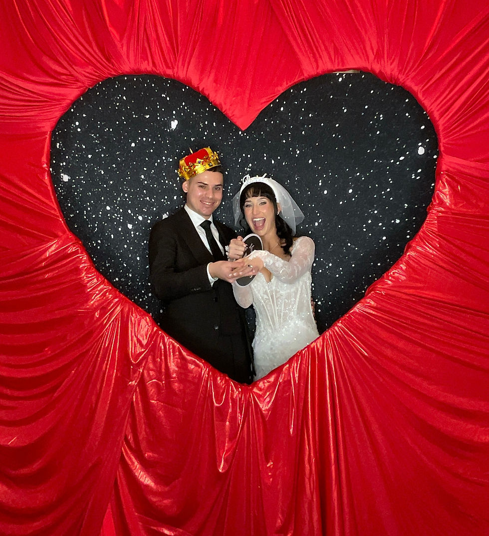 Couple posing inside a romantic red heart wedding backdrop at Andalusian Oaks in Williston, Florida. The Valentine-inspired setup features The Event Warehouse heart installation paired with SnapShotz Photo Booth Co.’s Black Sparkle Backdrop for a dramatic wedding photo booth experience.