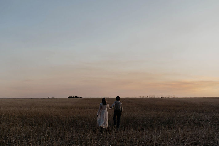 Photo of a couple at sunset in a harvested grain field.