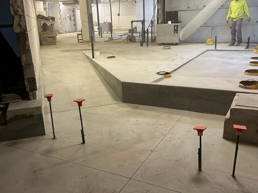 Concrete underpinning and ADA-compliant ramp construction in progress, showing newly poured structural slab and elevation transition designed to create accessible access within a renovated public facility.