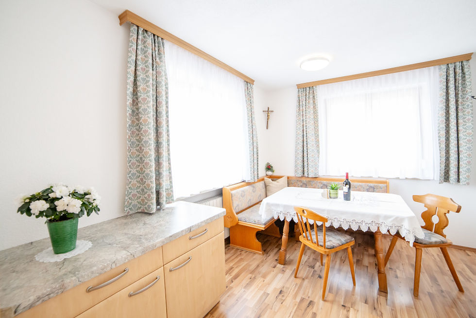 Wohn-Essbereich der Ferienwohnung Alpenblick. Heller Sitzbereich mit Eckbank,Tisch und zwei Fenstern