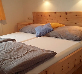 Swiss pine bed with grey bed cover and lights above