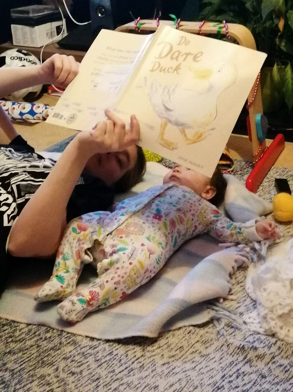 Amy laying on the floor reading to baby