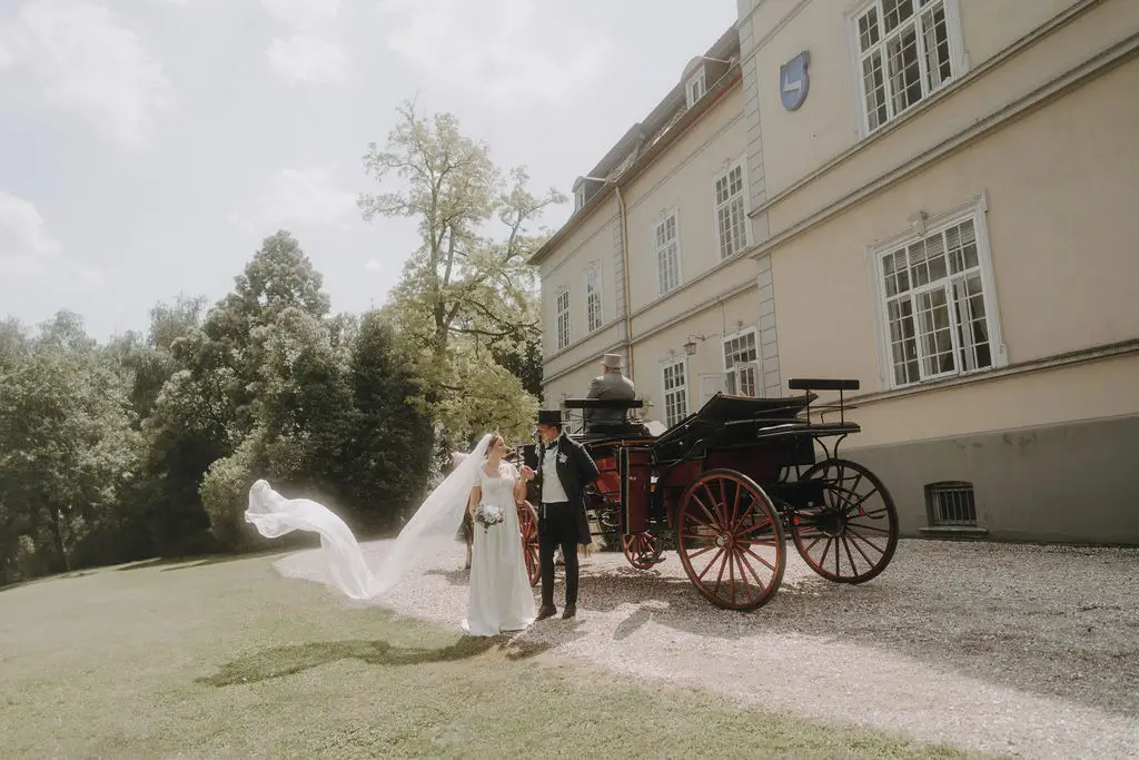 Braut vor Kutsche mit langem Schleier im Bridgertonstil