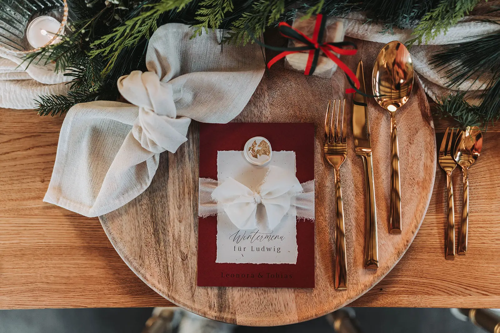 Menükarte mit Schleife, Siegel und Blattgold auf festlich gedecktem Tisch