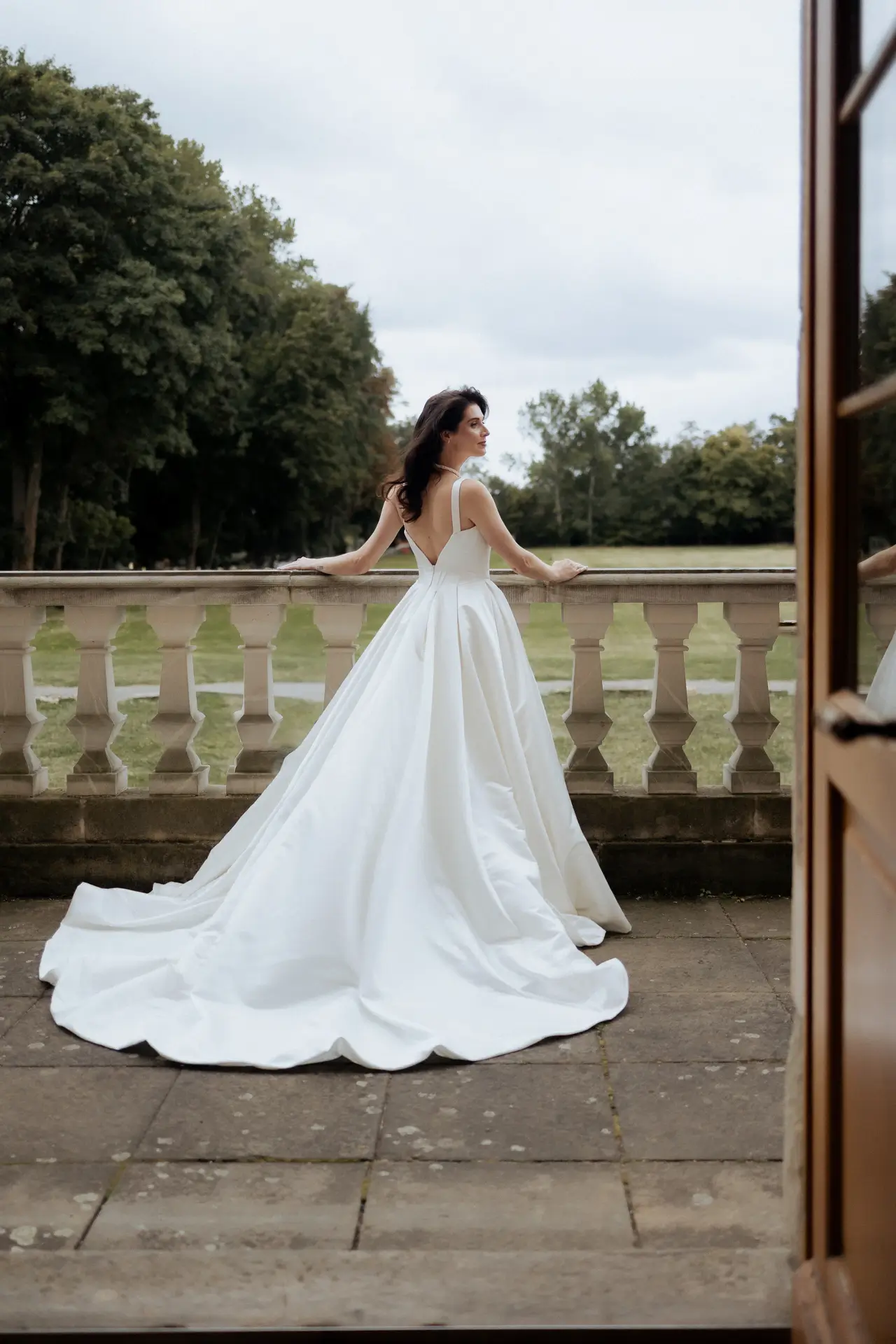 Braut auf Balkon Schlosshochzeit mit langer Schleppe