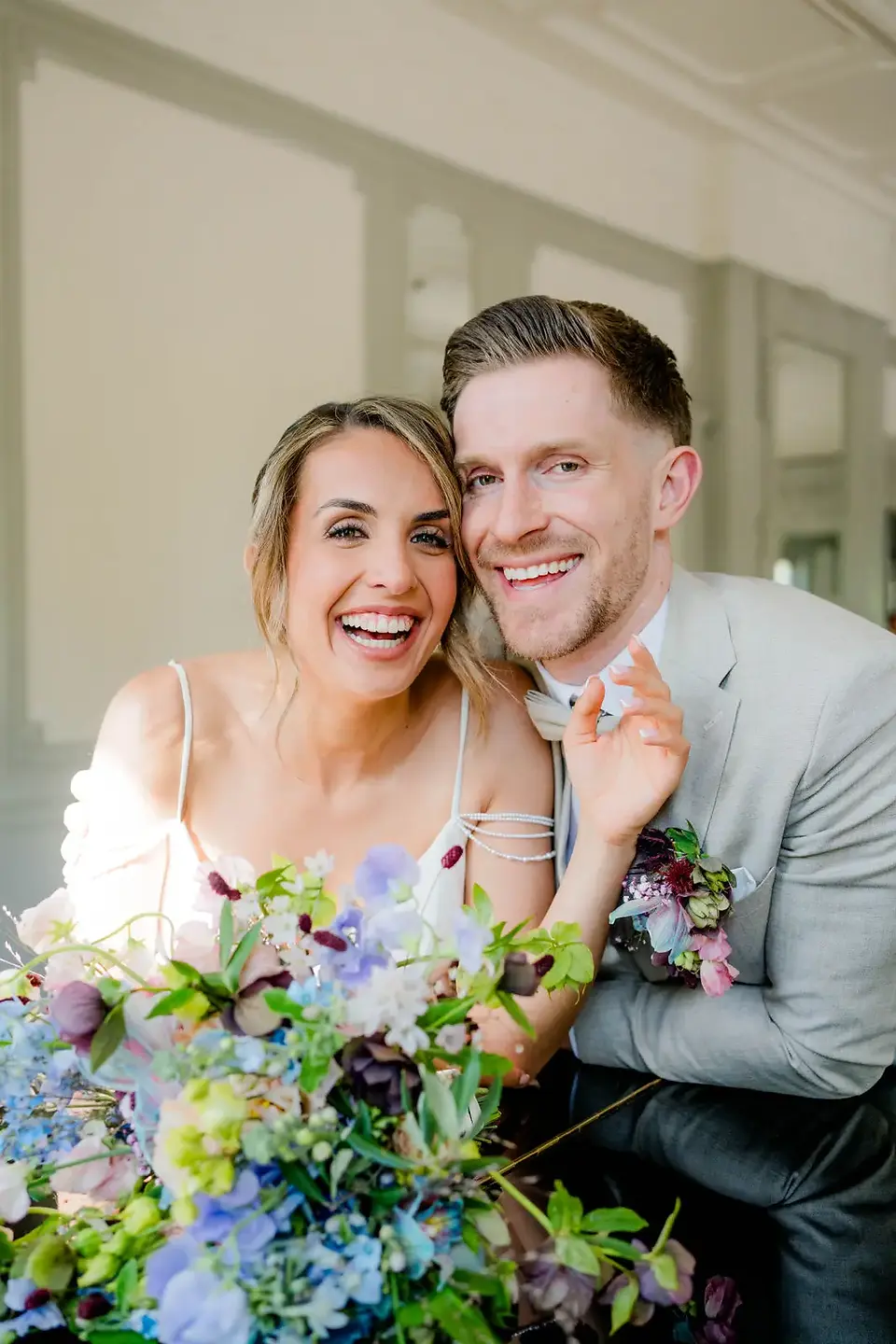 Lachendes Hochzeitspaar mit Brautstrauß