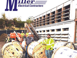 A team of Miller Electrical Contractors workers stands on a gravel job site next to large wooden reels of Service Wire Co. electrical cable. Two workers in the foreground, one wearing a hard hat and the other in a high-visibility yellow jacket, pose with the reels. Additional crew members and construction equipment are visible in the background. Logos for "CleanSpark" and "Miller Electrical Contractors" are prominently displayed at the top of the image.