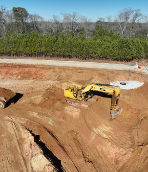 Excavator loading soil into a dump truck during active site grading and excavation at a commercial construction site by United Grading & Excavating.