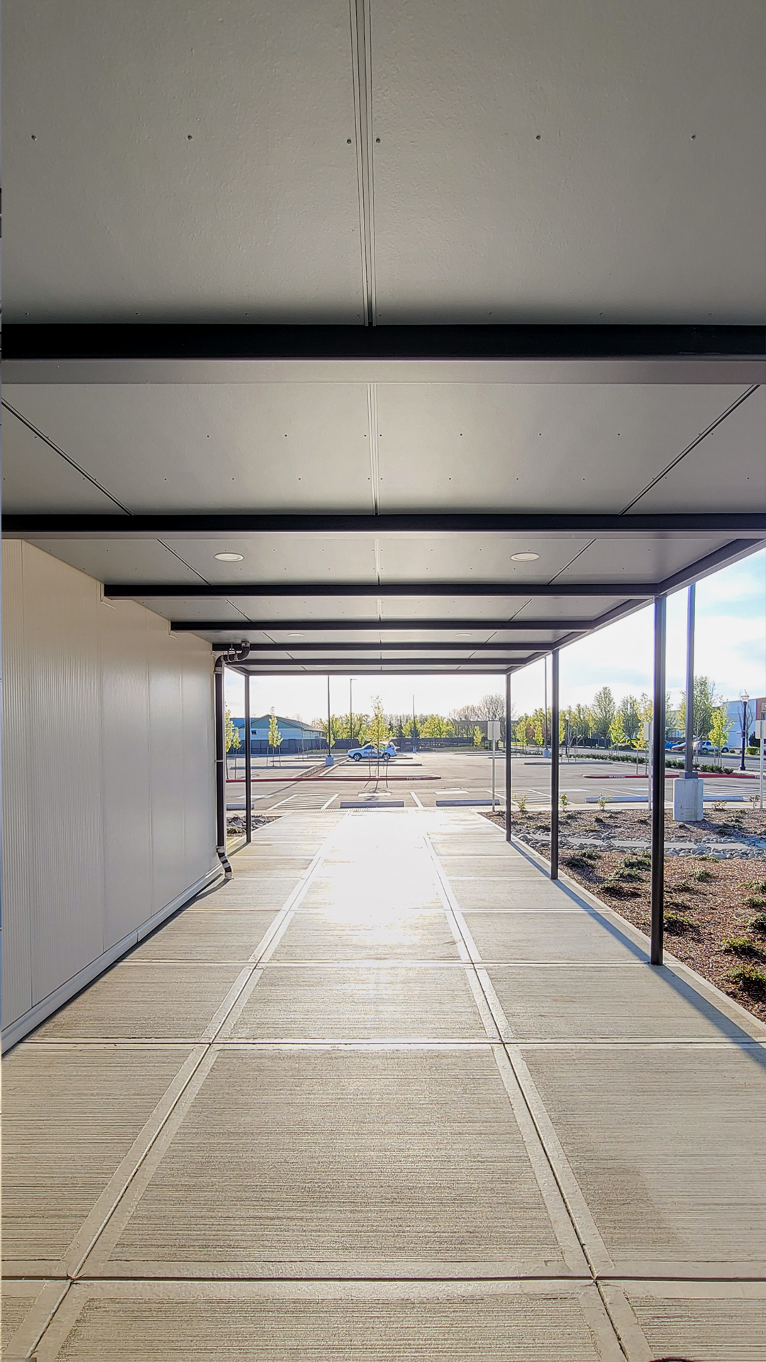 Photography showing the modern-industrial exterior design of NW Line JATC after commercial siding, window & soffit installation by StraightLine Exteriors in Battle Ground, Washington 98604. This photo showcases James Hardie fiber cement Architectural Collection Panels in Fine Sand installed on covered walkway soffit using Tamlyn Architectural Trim & Channel.