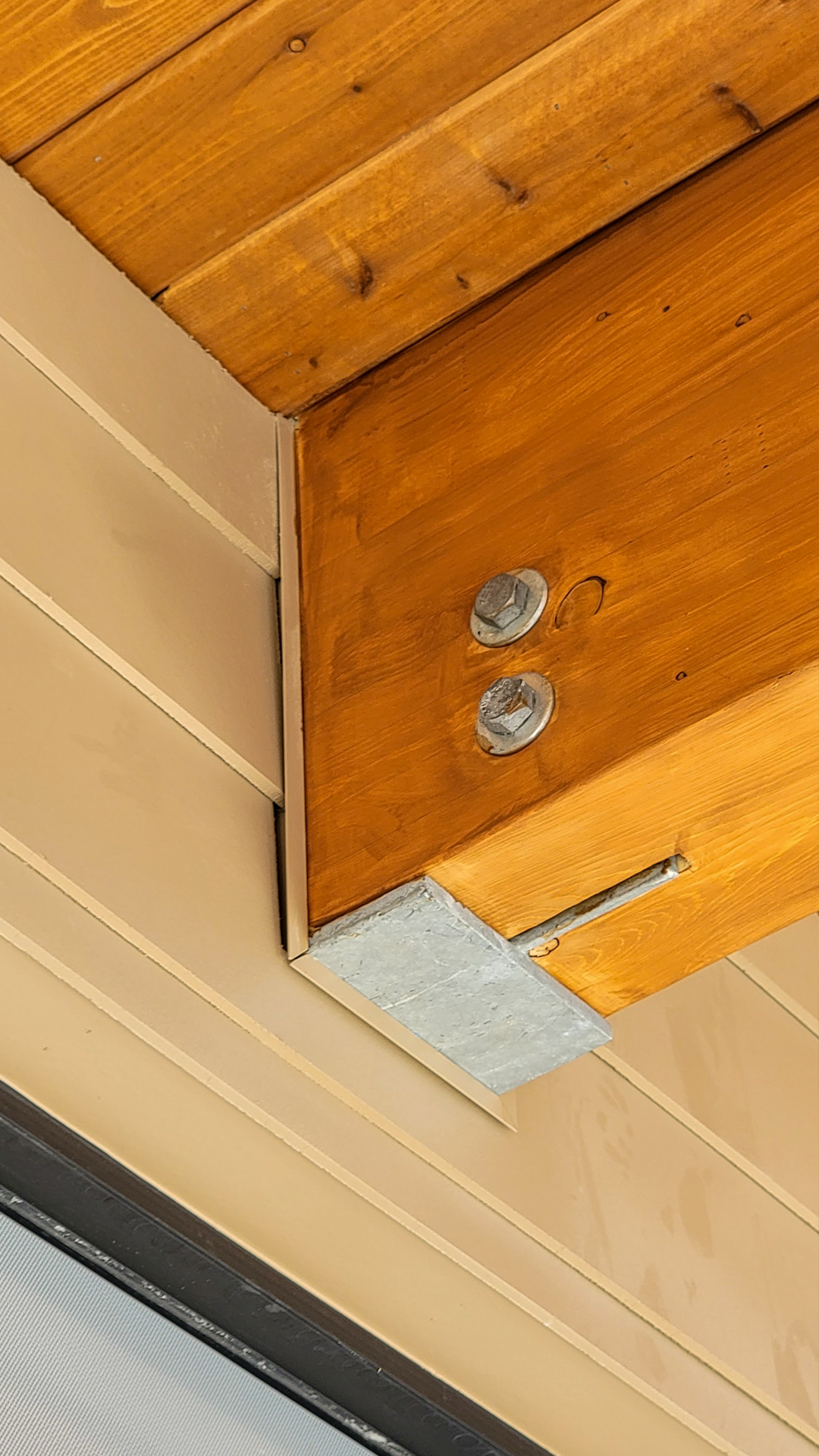 Mid afternoon photography showing the bracket and trim connection of stained cedar beams on Hardie Plank Lap Siding. Photo of Cascade Furniture & Mattress after commercial siding, soffit, post & beam installation by StraightLine Exteriors. 