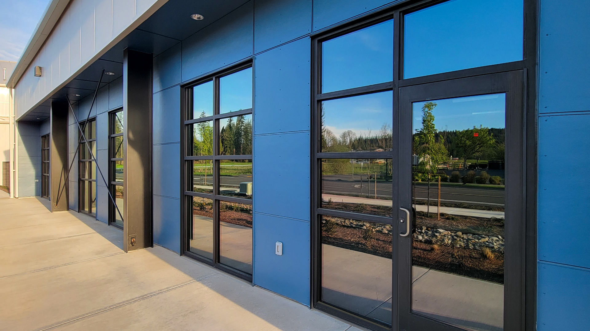 Mid day ground level photograph showing the new Northwest Line Joint Apprenticeship Training Facility (JATC) exterior design and office & classroom exterior elevation. Installed products include James Hardie fiber cement siding Architectural Collection Panels in the texture Fine Sand installed using Tamlyn Architectural Trim & Channel and exposed fasteners. This product was installed by StraightLine Exteriors in Battle Ground, Washington 98604. 