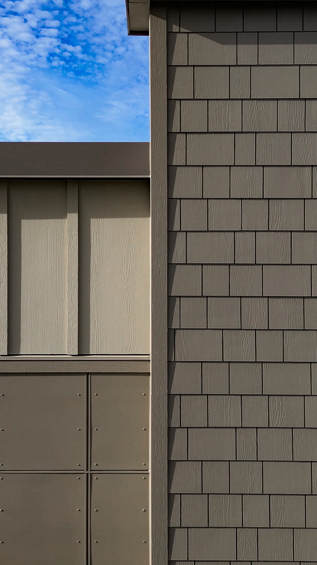 Mid-day fiber cement siding product photo showing the mix of Batten Board & Straight Edge Shingle siding products as well as Hardie Architectural Panels & exterior design after commercial siding installation by StraightLine Exteriors at Pioneer Village in Ridgefield, Washington 98642.