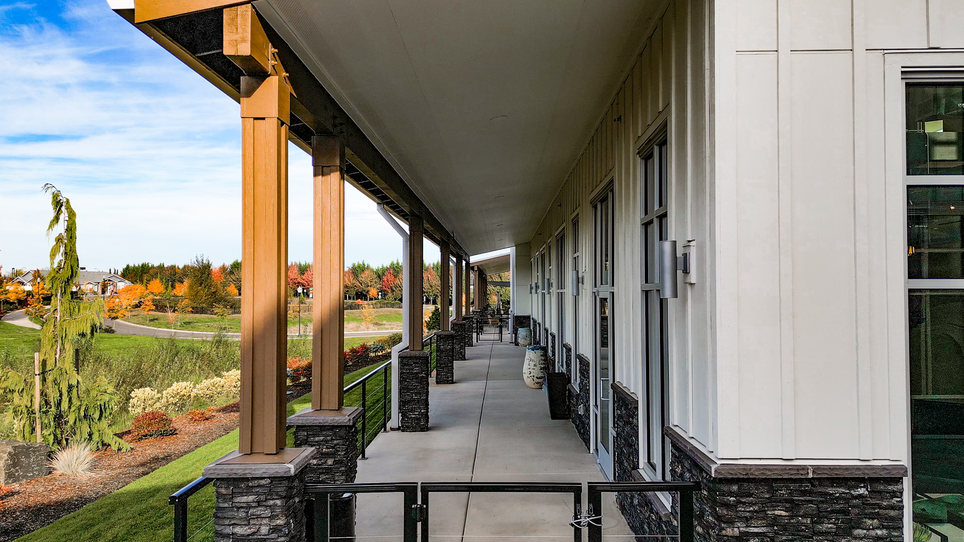 Mid-day photo showing the rear, covered, exterior design of Buildings 5-8 after commercial siding installation by StraightLine Exteriors at Pioneer Village in Ridgefield, Washington 98642. Products include James Hardie® Fiber Cement : Hardie Panel Vertical Siding (Board & Batten) and Hardie Soffit Panels.