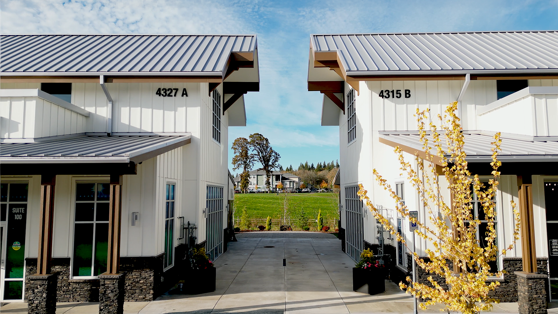 Mid-day photo showing the exterior design and breezeway walkthrough of Buildings 6 & 7 after commercial siding installation by StraightLine Exteriors at Pioneer Village in Ridgefield, Washington 98642. Products include James Hardie® Fiber Cement : Hardie Panel Vertical Siding (Board & Batten) and Hardie Soffit Panels.