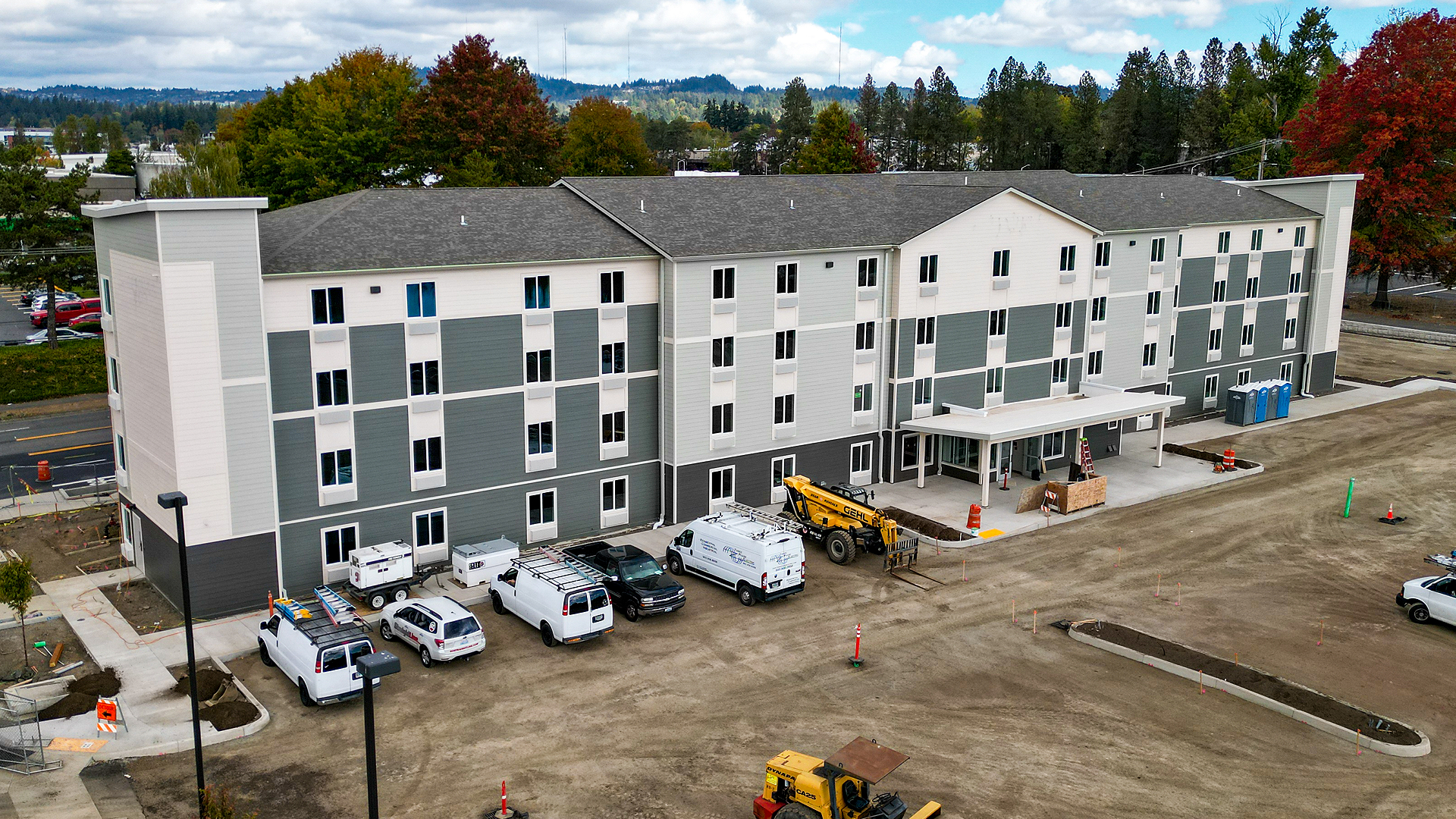 Mid-day aerial photography showing the size, scale and location of WoodSpring Suites Beaverton - Portland West, an extended stay hotel with 122 suites. Traditional residence-style exterior design of WoodSpring Suites Beaverton after commercial waterproofing, siding, window & soffit installation by StraightLine Exteriors in Beaverton, Oregon 97005. © StraightLine Exteriors 