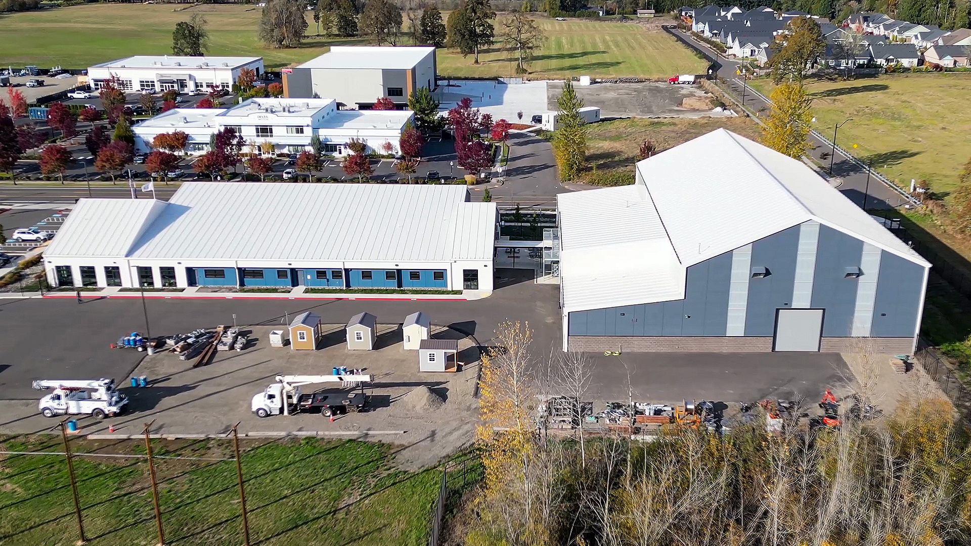 Mid day aerial photograph showing the new Northwest Line Joint Apprenticeship Training Facility (JATC) exterior design and rear elevation. Installed products include James Hardie fiber cement siding Architectural Collection Panels in the texture Fine Sand installed using Tamlyn Architectural Trim & Channel and exposed fasteners. This product was installed by StraightLine Exteriors in Battle Ground, Washington 98604. 