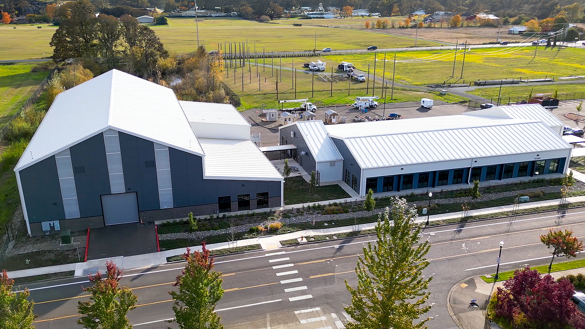 Mid day aerial photograph showing the new Northwest Line Joint Apprenticeship Training Facility (JATC) exterior design and rear corner elevation. Installed products include James Hardie fiber cement siding Architectural Collection Panels in the texture Fine Sand installed using Tamlyn Architectural Trim & Channel and exposed fasteners. This product was installed by StraightLine Exteriors in Battle Ground, Washington 98604. 