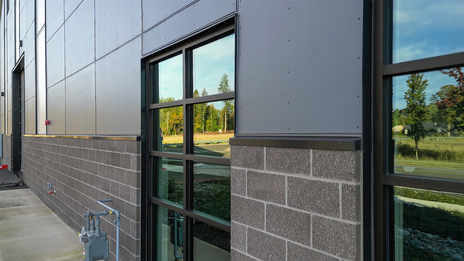 Close-up product photography of commercial storefront windows and stone wainscoting. This modern industrial exterior design was made using James Hardie® and Tamlyn® products. Commercial flashing & waterproofing by StraightLine Exteriors in Battle Ground, Washington 98604. 