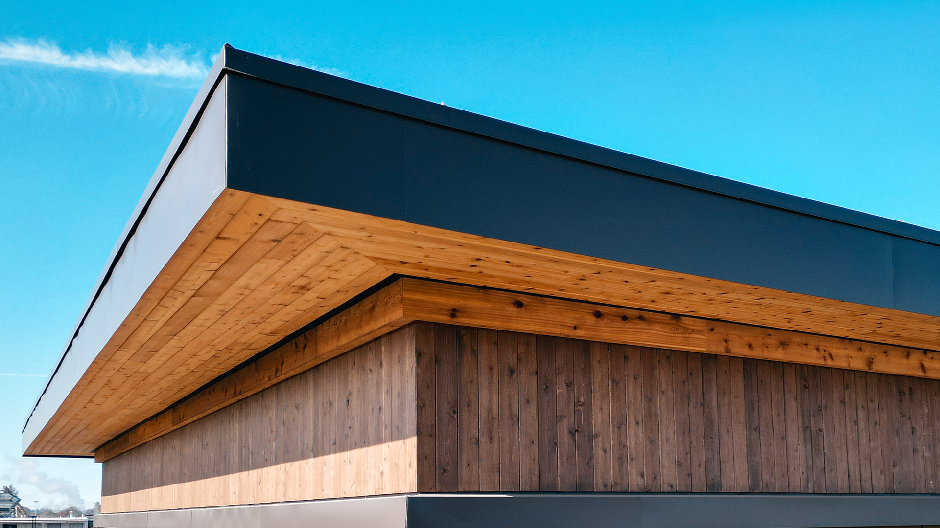 Mid-day aerial photo showing the stained cedar 1x6 tight knot tongue and groove product used in the parapet enclosed soffit (outdoor ceiling application) and siding (wall application) of Buildings 4 & 5. Commercial storefront property waterproofing, siding, flashing & soffit installation by StraightLine Exteriors in Camas, Washington 98607. 