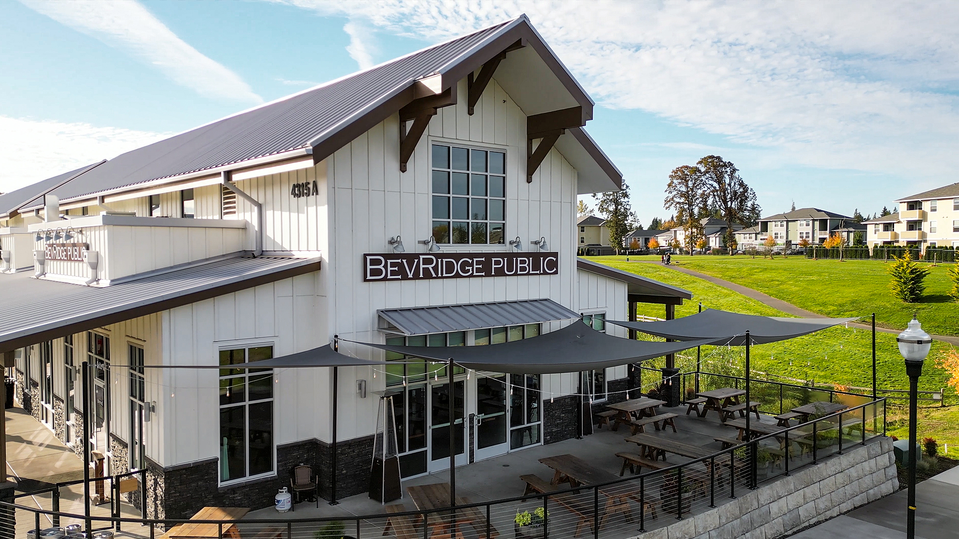 Mid-day photo showing the exterior design of Buildings 5 after commercial siding installation by StraightLine Exteriors at Pioneer Village in Ridgefield, Washington 98642. Products include James Hardie® Fiber Cement : Hardie Panel Vertical Siding (Board & Batten) and Hardie Soffit Panels.