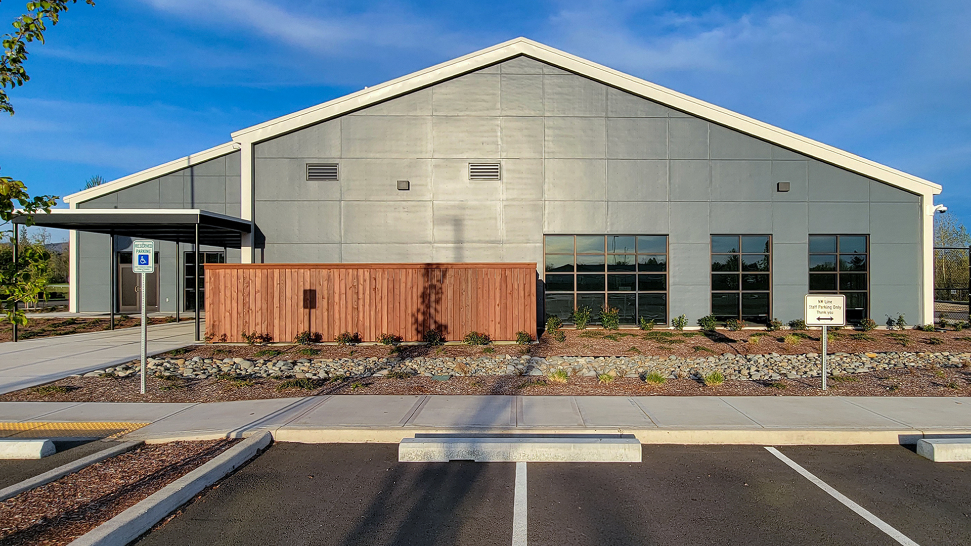 Late day ground level photograph showing the new Northwest Line Joint Apprenticeship Training Facility (JATC) exterior design and front office elevation. Installed products include James Hardie fiber cement siding Architectural Collection Panels in the texture Fine Sand installed using Tamlyn Architectural Trim & Channel and exposed fasteners. This product was installed by StraightLine Exteriors in Battle Ground, Washington 98604. 
