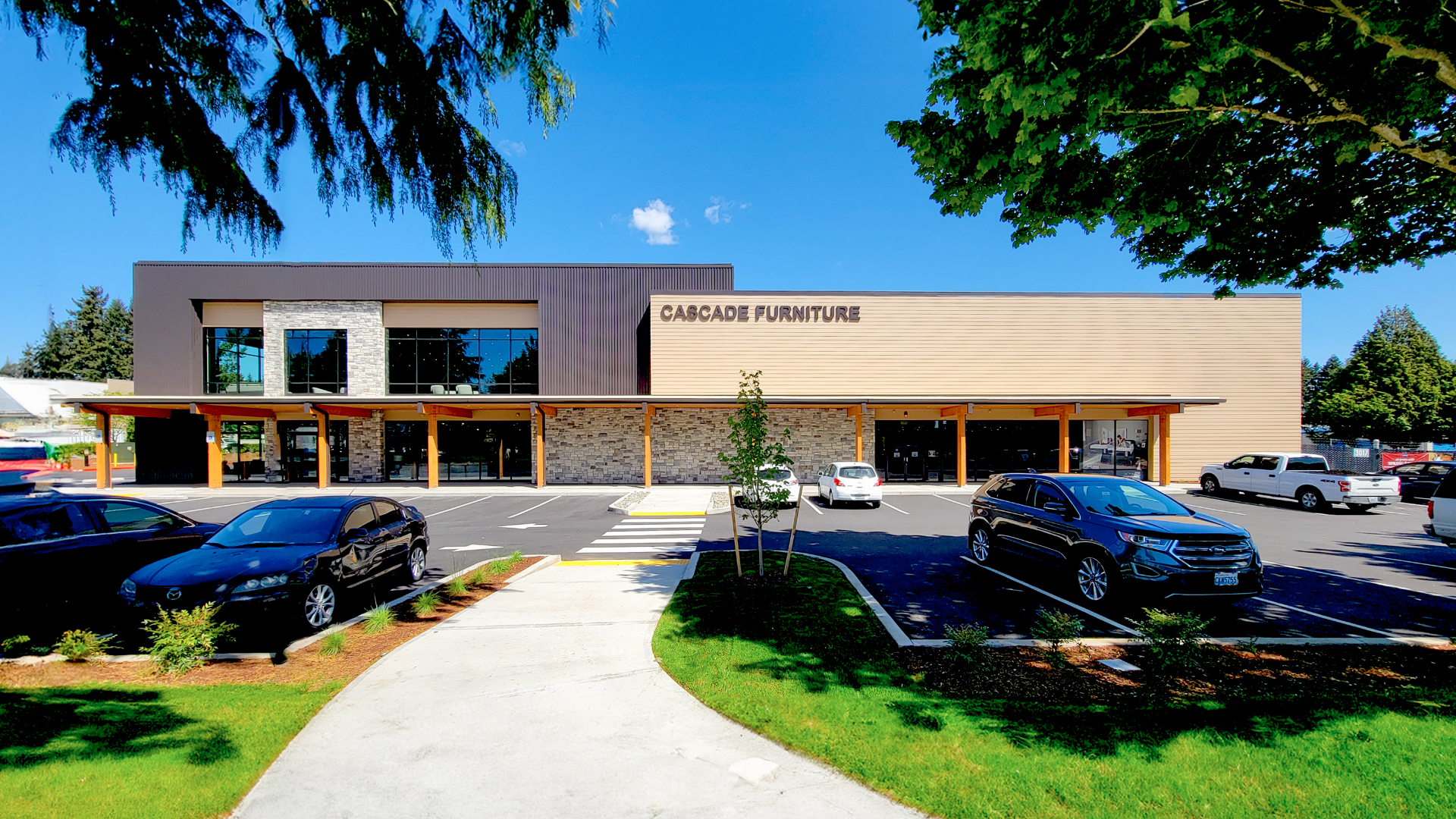 Mid day photography showing the front facade of Cascade Furniture & Mattress after commercial siding, soffit, post & beam installation by StraightLine Exteriors. This photo shows the entire front commercial storefront of Hardie® Plank Lap Siding & Stained Cedar accents.