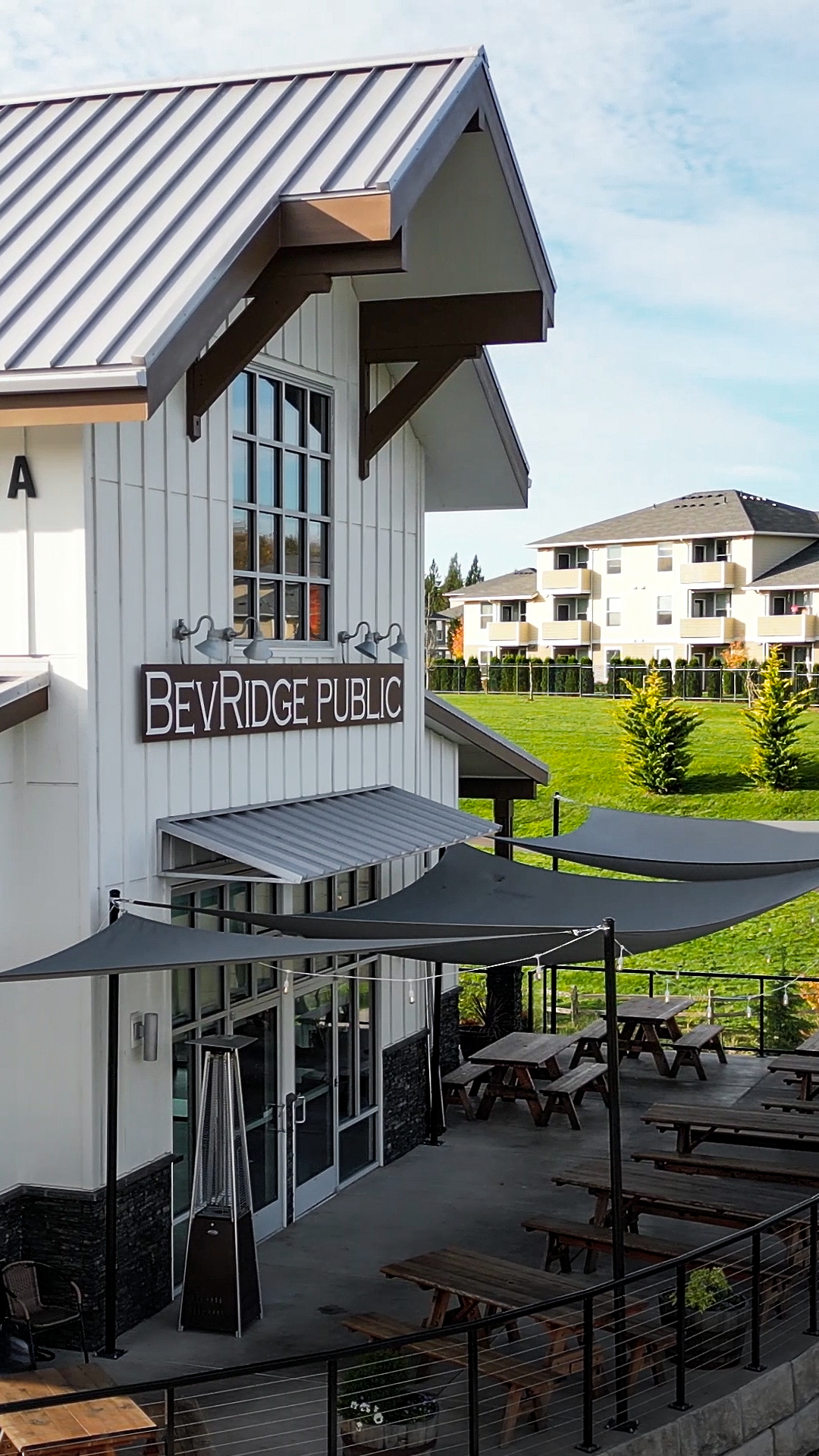 Mid-day photo showing the exterior design of Buildings 5 after commercial siding installation by StraightLine Exteriors at Pioneer Village in Ridgefield, Washington 98642. Products include James Hardie® Fiber Cement : Hardie Panel Vertical Siding (Board & Batten) and Hardie Soffit Panels.