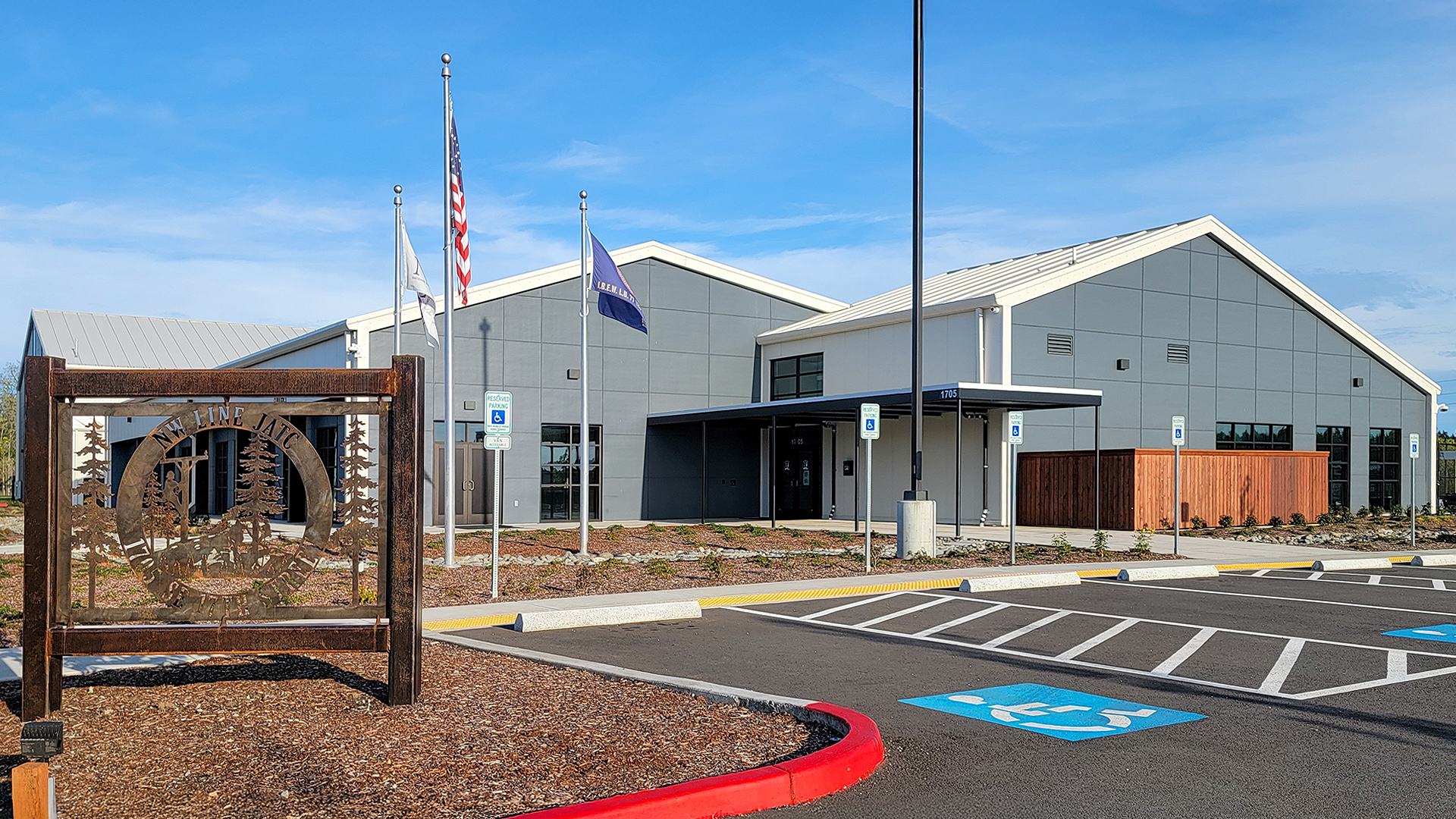 Mid day ground level photograph showing the new Northwest Line Joint Apprenticeship Training Facility (JATC) exterior design and front elevation. Installed products include James Hardie fiber cement siding Architectural Collection Panels in the texture Fine Sand installed using Tamlyn Architectural Trim & Channel and exposed fasteners. This product was installed by StraightLine Exteriors in Battle Ground, Washington 98604. 