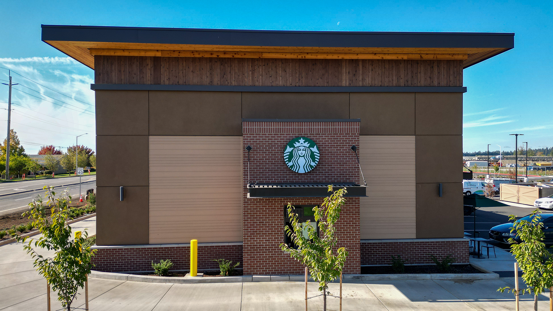 Mid-day aerial photo showing the East side wall (Drive-Thru) elevation of Building 4. Exterior features include stained cedar 1x6 tight knot t & g in the parapet enclosed soffit (outdoor ceiling application) and siding (wall application) of Building 4. Commercial storefront property waterproofing, siding, flashing & soffit installation by StraightLine Exteriors in Camas, Washington 98607. 