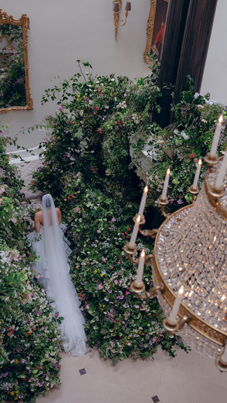An impressive floral display covering an entire staircase, with a bride in the middle wearing a floral embroidered veil