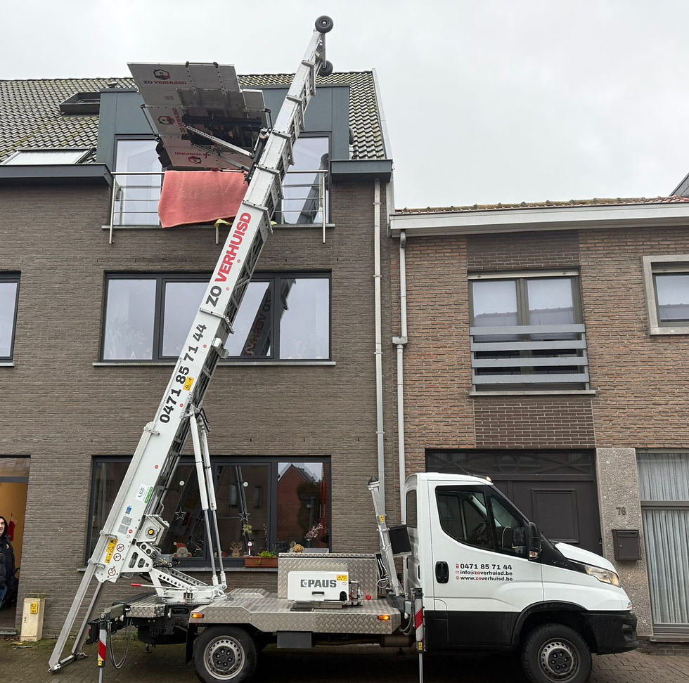 White truck with extended moving lift parked by a modern brick building. Text on the truck includes contact info and website. Overcast sky. zo verhuisd