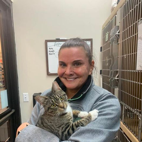 Smiling woman gently holding tabby cat