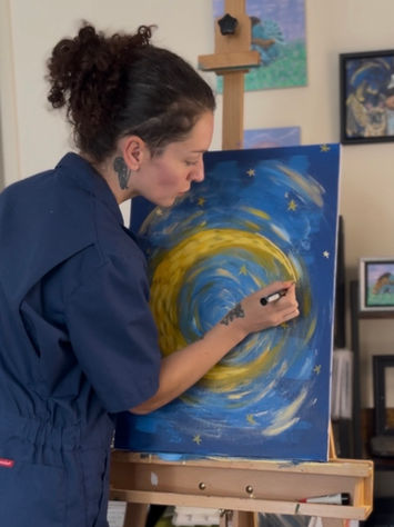 Jesseca Lou painting gold details onto a blue memorial artwork in her studio